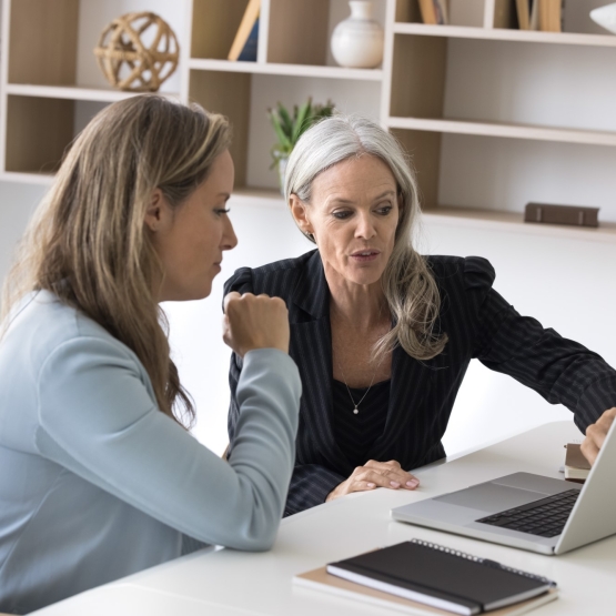 Professional consultation. Experienced senior businesswoman bank manager financial advisor meet with female client customer in work office give advice support explain contract details using notebook